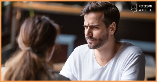 Man looking questioningly at a woman across a small table